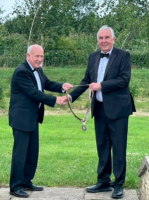 Outgoing President Mac Bryant (right) handing over Rotary chain of office to incoming President John Morton (left) outside Tennant’s at Leyburn.